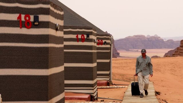 Wadi Rum, Jordan,  A man walks with bag in a boardwalk to check into a desert camp.