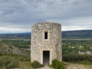 Chappe telegraph tower in stone at Orgon in the Alpilles with a beautiful landscape behind with the green Durance valley under a cloudy sky in Provence in France