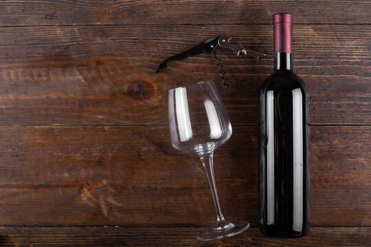Corkscrew, glass and bottle of red wine on a wooden background. Top view