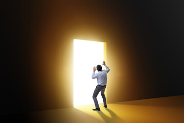 Businessman entering backlit door in escape concept