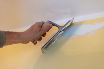 Close-up of hand plastering a yellow wall. Spackling walls. 