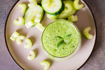 Fresh green cucumber and celery smoothie in glass for vegetarian diet top view closeup