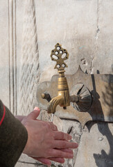 A woman washing her hands at a historical ottoman fountain. Istanbul Turkey