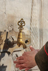 A woman washing her hands at a historical ottoman fountain. Istanbul Turkey