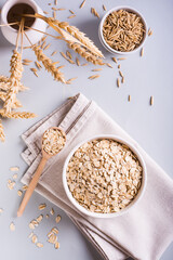 A plate with dry oatmeal and ears of oats on a gray background. Top and vertical view