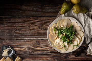 Pear carpaccio with arugula and nuts on a wooden table