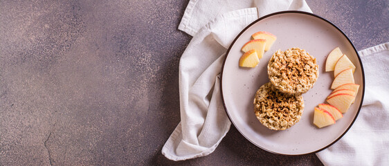 Appetizing crumble of apples and oatmeal on a plate and fruits on the table. Top view web banner