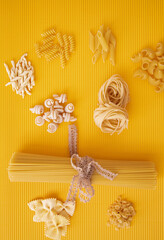 Italian pasta on a yellow background,top view,spaghetti and fettuccini, there is a place for the inscription