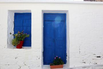 Vacation destination Chios Greece: typical Greek blue wooden doors and shutters on white wall in Volissos in the north of the Aegean island. Attractive place to be, with few tourists so far.