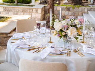 Table at luxury wedding reception event. Beautiful flowers on table and serving dishes and glasses and decoration