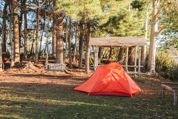 Orange tent in a camping area in the summer morning hour in countryside. Copy space