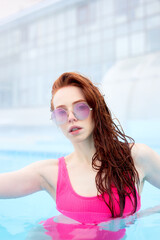 Fototapeta na wymiar chic woman in luxury swimwear with long ginger hair posing to the camera outdoors. sexuality, love concept. relax, beauty , blurred background, heath body care, wellness, fitness, spa