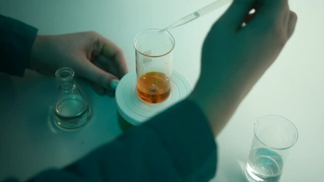 Scientist using a pipette to put solution in glass flask. Stock footage. Concept of medicine and chemistry.
