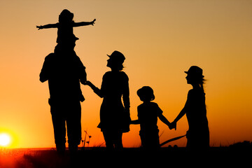 Fototapeta premium A Happy family by the sea at sunset in travel silhouette in nature