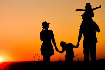 Fototapeta na wymiar A Happy family by the sea at sunset in travel silhouette in nature
