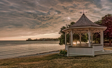Niagara-on-the-Lake, Ontario, Canada: - July 9, 2016: Sunrise at Queen's Royal Park with the gazebo under a dramatic  sky and Fort Niagara in the distance
