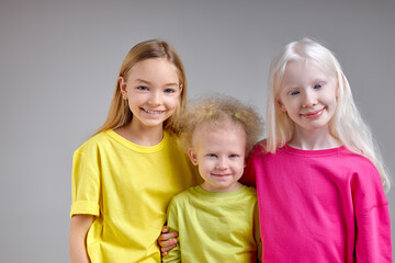 Fototapeta na wymiar Diverse happy kids isolated on white background. Smiling and happy children look at camera, beauty, childhood, blonde girl embrace her sisters and roll her eyes