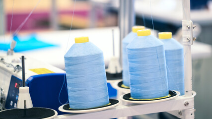 Reels of textile yarn blue thread at industrial weaving manufacturing machine,  textile fabric...
