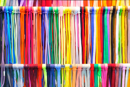 Mix colorful hanging vertical stripe textile, fabrics, cloths on the rack. Texture of multicolored fabrics close up.