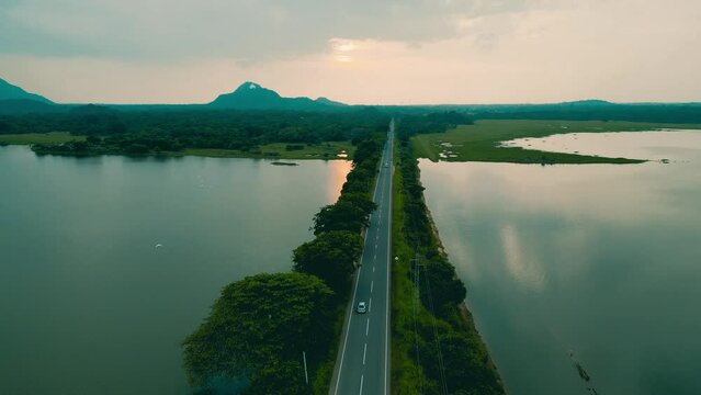 Drone aerial footage of a Road built mid of a Lake moving backward