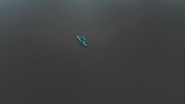 Cinematic aerial drone view of a wooden fishing boat sailing on a lake