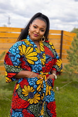 Summer portrait of beautiful african american woman in colourful dress wear standing on backyard. Suburban lifestyle and chilling on weekend in countryside and inclusion with diversity concept