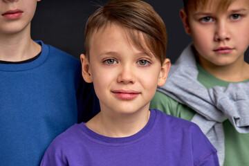 brownhaired handsome boy with greeen eyes posing to camera, his serious attractive brothers in th...