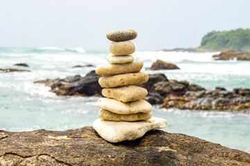 Fototapeta na wymiar Pyramid of relaxation made of sea stones on the coast of Sri Lanka. Photography for tourism background, design and advertising