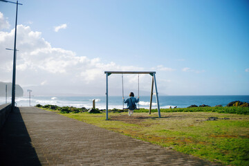 girl on a swing on the background of the ocean coast
