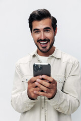 Close-up portrait man holding a phone smile typing a message, chatting online freelance work on a white isolated background, fashionable clothing style, copy space, space for text