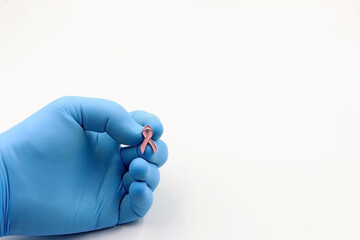 Doctor's or researcher's glove with a pink bow. Fighting cancer