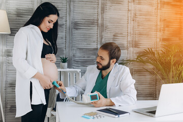 A gynecologist examines a pregnant woman. Fetal doppler heart auscultation.