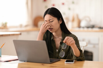 Overworked asian woman independent contractor sitting in front of laptop