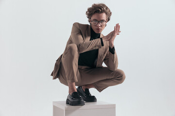 businessman squatting on wooden chair and rubbing his hands