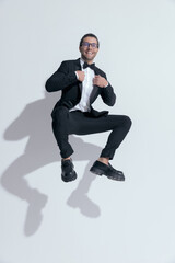 businessman jumping and squatting while fixing his tux