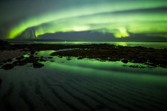 Aurora borealis reflecting in calm ocean tidal pool Iceland - Powered by Adobe