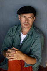 An attractive man in a hat and red pants is looking at the camera. Handsome male