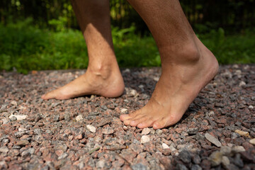 A man walks barefoot on small stones