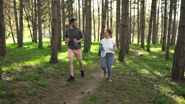 Beautiful overweight female jogging with her friend through the forest.