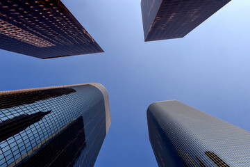 Skyscrapers, one of the buildings in a quadrangular shape, with reflections, and the beautiful blue sky appears at an angle from the bottom
