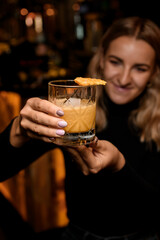 great view on glass of cocktail with ice decorated with waffle in female hands