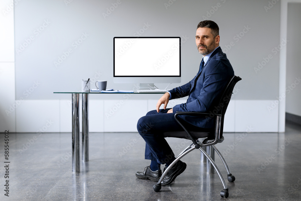 Aufkleber confident middle aged businessman in suit sitting on desk with computer monitor with blank screen at
