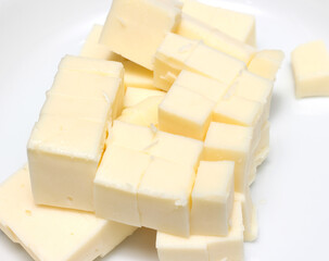 piece of cheese cut into cubes. diced cheese with selective focus. dairy product ready to be consumed.