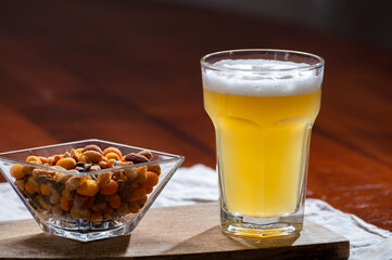 Glass of Belgian white unfiltered beer with notes of coriander and orange peer and different snack nuts