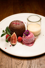 Tasty chocolate cake with ice and jar of cream served on white plate