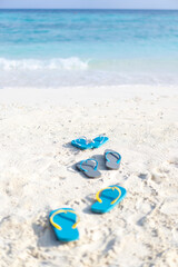 Three pairs of flip flops on the beach on the background of ocean in the Maldives. Family vacation