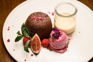 Close-up of sweet chocolate cake with ice and jar of cream served on white plate