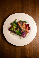 top view on plate with roasted duck leg garnished with apples and herbs