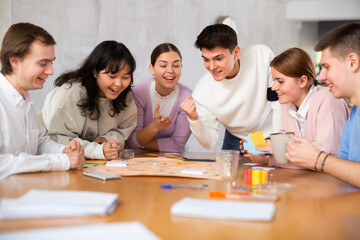 Group of happy young people playing board game