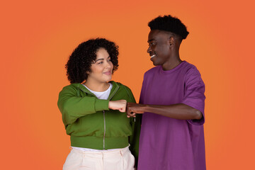 Happy mixed race couple give fist bump over red background